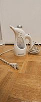 Front view of Proctor Silex garment steamer with cord and plug visible on parquet floor