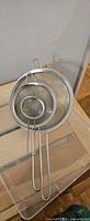 Three nested metal mesh sieves with looped handles