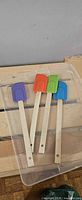 Top view of four multi-color silicone-head wooden spatulas