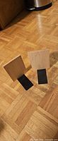 Two hardwood bookends with black metal bases standing on floor