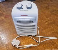 Front view of white fan-forced space heater with controls and cord