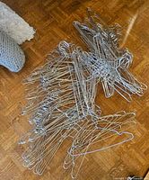 Pile of silver metal wire clothes hangers on floor