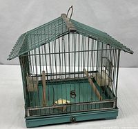 Full view of blue-green wire bird cage with pitched roof