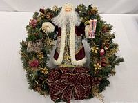 Front view of 20 in Christmas wreath featuring Santa figure, ribbon bow, pinecones and berries
