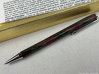 Full view of pen beside gift box showing hardwood grain and chrome hardware