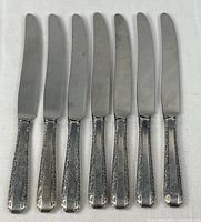 Seven Towle stainless dinner knives laid out blade up
