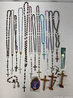 Full lot overview showing rosaries, crucifixes, bracelets, prayer card and plaque