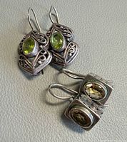 Two pairs of silver gemstone earrings displayed