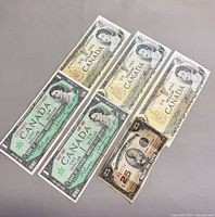 Front of three 1973 $1 notes, two 1967 $1 notes and one 25-cent note