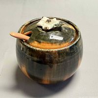 angled view of signed ceramic lidded sugar bowl with spoon inserted