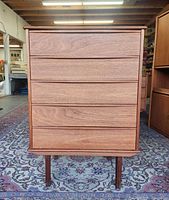 Front view showing five drawer fronts, teak grain, legs