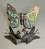 Front view of brooch and pair of earrings showing abalone inlay and butterfly shapes