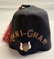 Full view of black fez showing red tassel, gold cord lettering and Viking pin