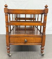 Front view showing slatted rack, drawer, turned legs and casters