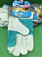 Front view of gloves showing teal leather palms, grey fingers and packaging header card