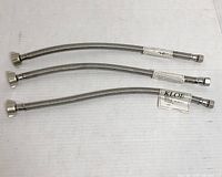 Three stainless steel braided toilet connectors laid flat