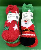 Two labeled bundles of George fuzzy socks showing Santa and star designs