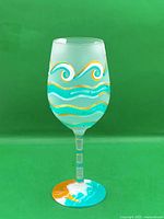 Full view of hand-painted wine glass on green backdrop