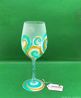 Full view of hand-painted wine glass with tag attached