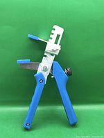 Left side view of blue-handled tile levelling pliers showing stepped jaw and adjustment knob.