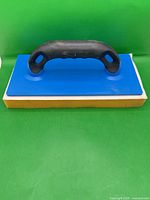 Top view showing blue base, yellow sponge, black handle