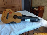 Full view of acoustic guitar resting in open hard case showing painted top and slot headstock