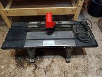 Front view of Craftsman router mounted on table stand with fence and coiled cord visible