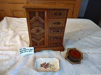 Full view of wooden jewelry cabinet, music box mechanism, and porcelain dish on table