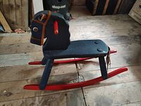 Side view of blue wooden rocking horse with red runners and leather bridle