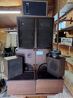 stack of various brown wood veneer speaker cabinets and loose driver visible