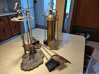 Both fireplace tool sets with stands and loose extra tools displayed on countertop