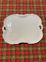 Front of white scalloped platter showing glaze and handles