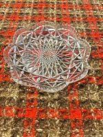 Top view of clear pressed glass dish on patterned fabric