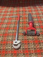 Basin wrench and carpet seam roller side by side on carpet background