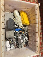 Top view of bin showing twine spool, yellow box, grey tool case, assorted hardware