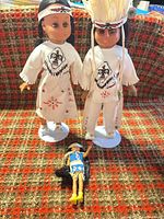 Two large Carlson dolls on stands with small blue-dressed doll lying in front