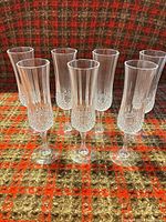Full set of seven crystal champagne flutes standing upright on patterned surface