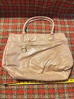 Front view of beige faux snakeskin tote bag with exterior zip pocket and EL charm, tape measure showing width ~17 in