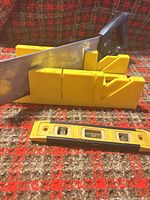 Miter box, back saw inserted, torpedo level in front