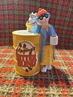 Front view of ceramic coin bank showing Maxine, Floyd, and coffee can graphic