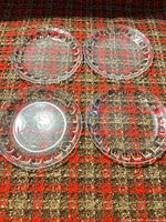 Top view of four clear glass plates showing complete Candlewick beaded rims