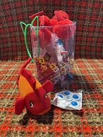 Container of novelty pens, plush goldfish, packaged fidget spinner