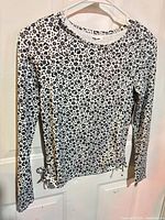 Front view of white and black floral long sleeve knit top on hanger