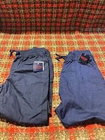 Both pairs of navy Kids Club pants with tags visible