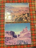 Two 8x10 color photographs in sleeves on patterned surface
