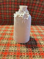 Front view of white ceramic vase showing floral appliqués