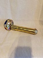 Side view of brass kaleidoscope showing tubular body and colored wheel