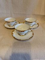 Three teacups each on matching saucers showing overall design and gilt decoration