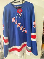 Front of blue New York Rangers jersey, laced neck, player number 9 partially visible on sleeve