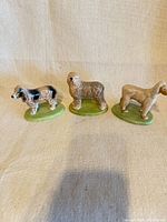 All three dog figurines side by side on fabric background